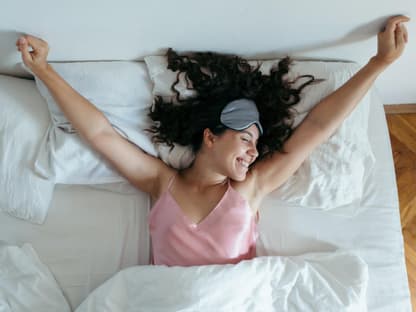 Anti-Aging-Nachtcreme Frau mit Schlafmaske streckt sich