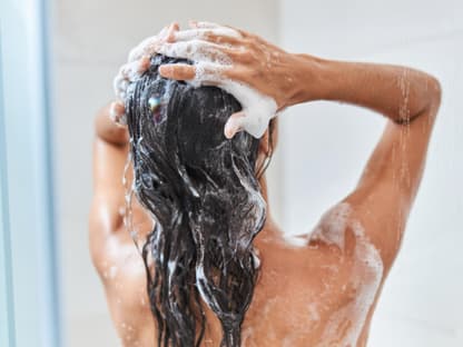 Haare waschen mit 60-180-Regel Frau wäscht unter der Dusche Haare