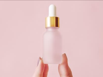 Hyaluron-Serum reduziert Frau mit Serum-Flasche zwischen Finge
