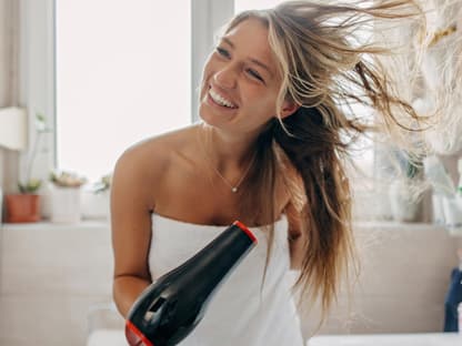 Föhnspray für 3 Tage Volumen Frau föhnt sich Haare