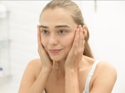 Hautpflege mit chemischen Peeling Frau mit nassem Gesicht schaut in Spiegel