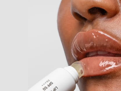 Volle Lippen dank Tinted Gloss Frau trägt Lipgloss auf