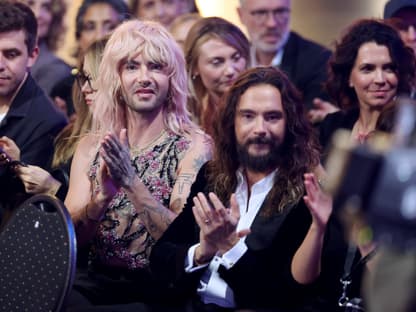 Bill und Tom Kaulitz sitzen im Publikum und klatschen mit ernster Miene