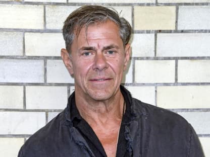 Sven Martinek steht vor einer Wand