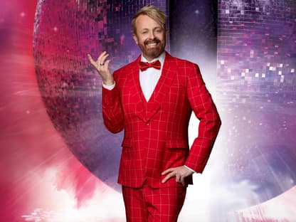 Ross Antony im roten Anzug vor Discokugel