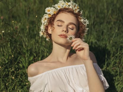 Frau mit Blumenkranz auf grüner Wiese