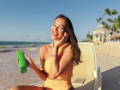 Frau cremt sich am Strand ein