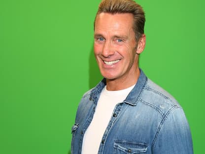 Jürgen Milski strahlt vor einer grünen Wand