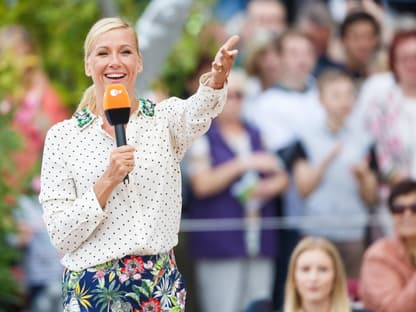 Andrea Kiewel schaut freudig und zeigt aufs Publikum.