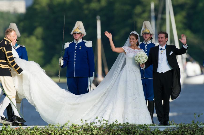 Das taillierte Brautkleid mit kurzen Ärmeln und vier Meter langer Schleppe gestaltete er mit elfenbeinfarbener Chantilly-Spitze.