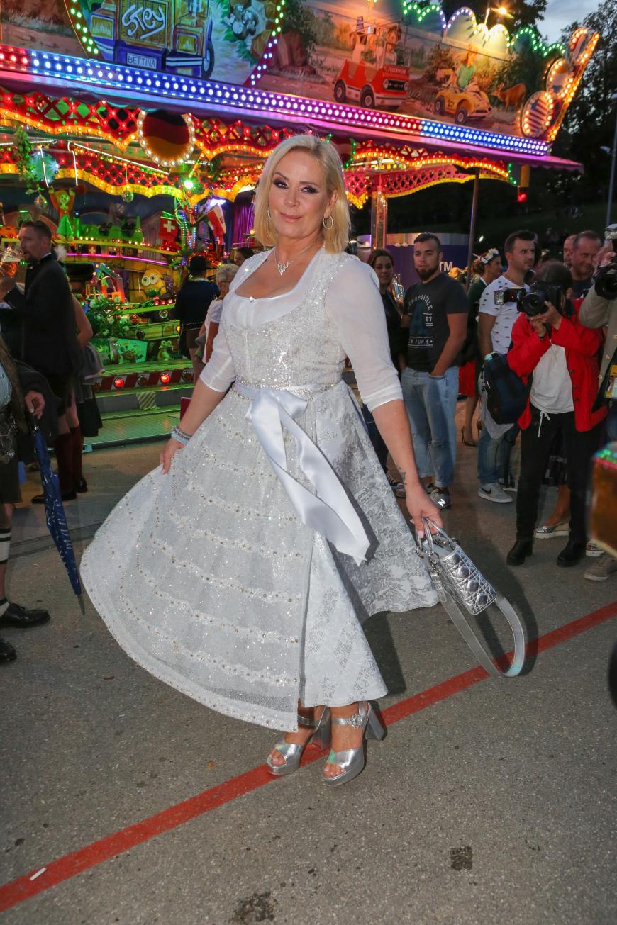 Gekonnt schwingt Claudia Effenberg den Rock ihres silbernen Dirndls. Dazu kombiniert sie farblich abgestimmten Schmuck, Tasche und Schuhe.