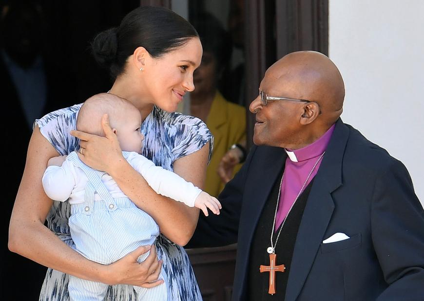 In blau-weiß-gestreifter Latzhose ging es für Archie zu Besuch bei Friedensnobelpreisträger Desmond Tutu, der sichtlich erfreut war, den Säugling kennenzulernen.