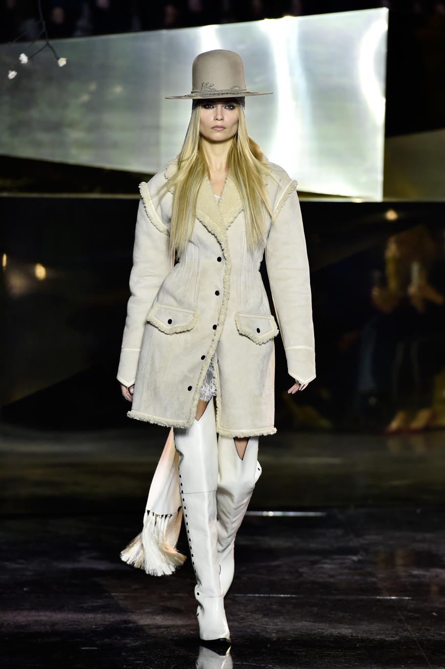 Der Opening-Look: Natasha Poly in Gaucho-Hut, Lammfellmantel und Overknee-Boots