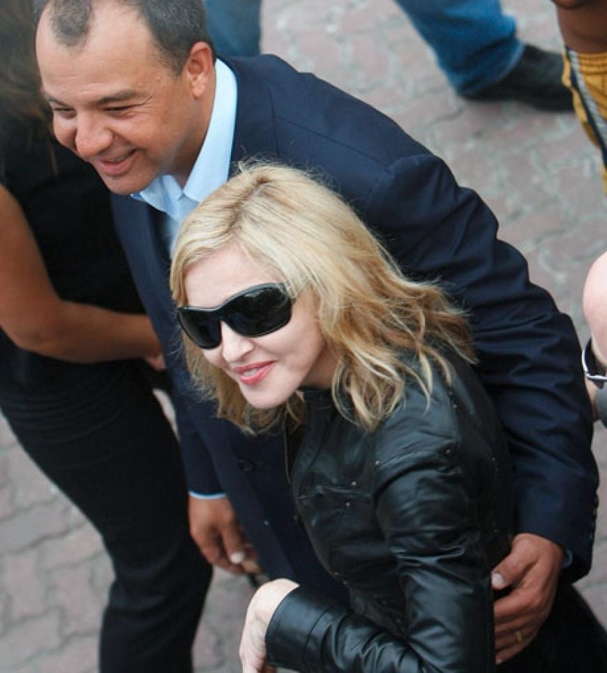 Madonna wird von Rios Gouverneur, Sergio Cabral, umarmt und durch die Viertel geführt