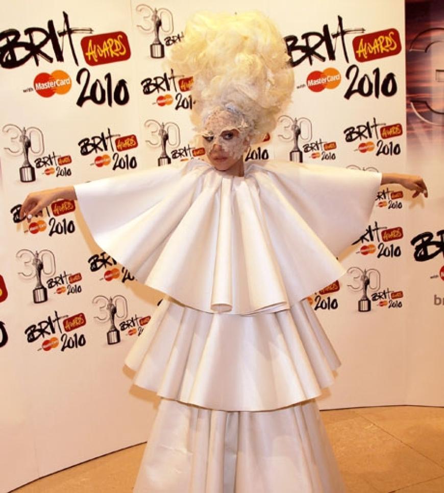 Doch sie überraschte alle anwesenden Gäste und erschien in einem ihrer sonderbaren Outfits. Diesmal trug die Sängerin einen weißen dreistufigen Mantel. Die Turmfrisur und ihre weiße Maske aus Spitze rundete das Ensemble ab
