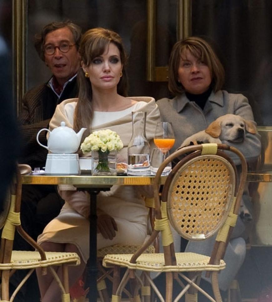 Lady-like und mit ärmelhohen Wildlederhandschuhen: Angelina Jolie sitzt in einem Pariser Café beim Petit-Déjeuner