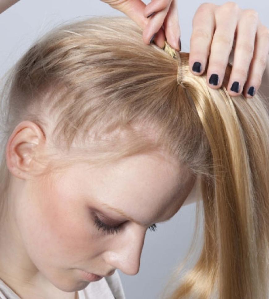 Step 2: Damit der Dutt einen gewollt zerzausten Effekt bekommt, die Extensions vor dem Anklipsen an den ´Enden mit einem Kamm leicht tou´pie´ren. Tresse leicht kopfüber am Gummiband ansetzen und um den gesamten Zopf wickeln, den ´letzen Klips unter das Gummiband stecken und gut befestigen. Je nach Geschmack mit weiteren Haarteilen wiederholen