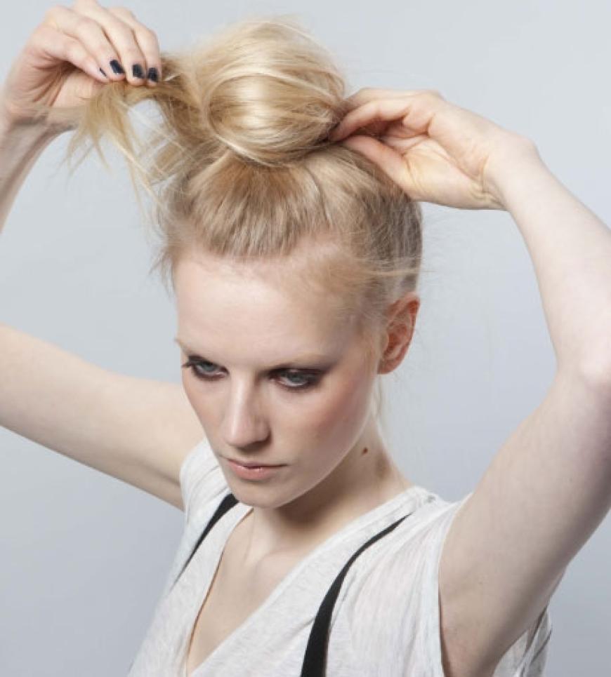 Step 4: Den Dutt nun mit mehreren Klammern feststecken und stabilisieren. Für zusätzlichen Halt noch mit Haarspray einnebeln. Zum Schluss einzelne feine Strähnchen mit dem Stielkamm herauszupfen, noch einmal etwas mattierende Paste in den Handflächen verreiben und seitlich in die Ansätze rubbeln, damit einzelne Härchen abstehen