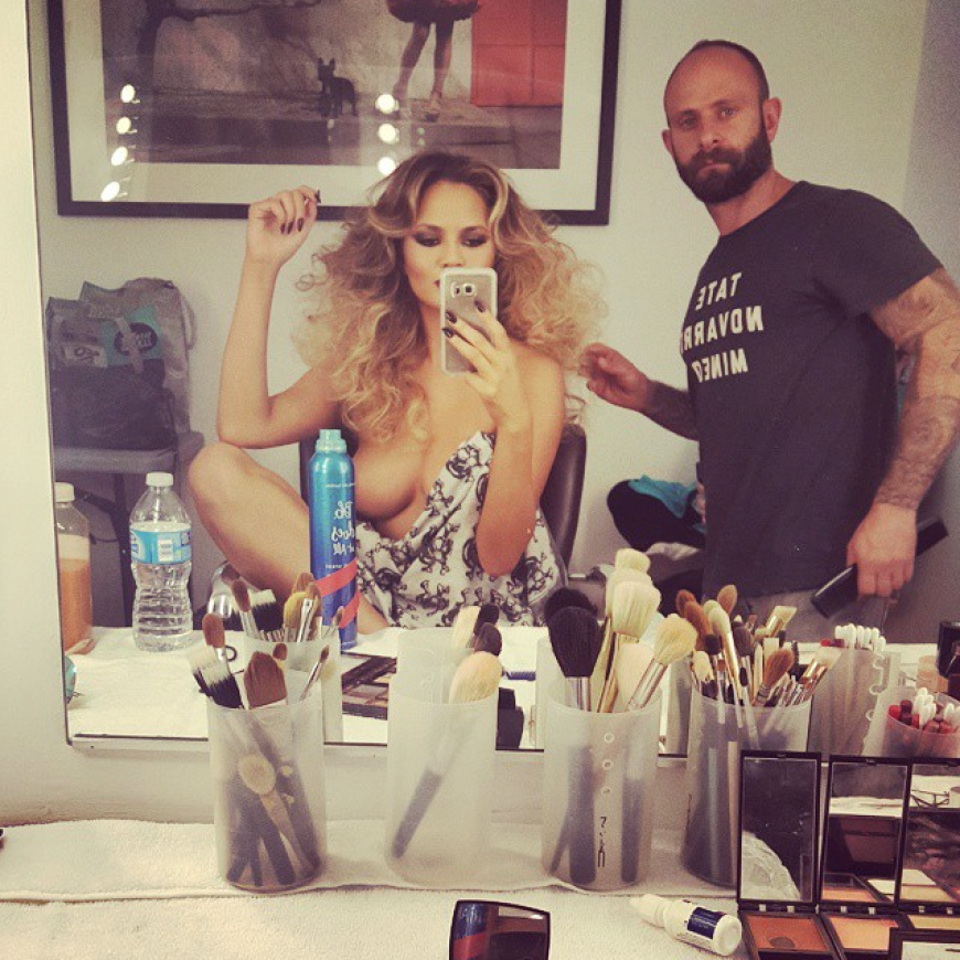 Boobs-Alarm! Model Chrissy Teigen ist in der Maske so von ihren Brüsten fasziniert, dass sie sie kurzerhand abknipsen muss. Ihr Visagist scheint etwas perplex.