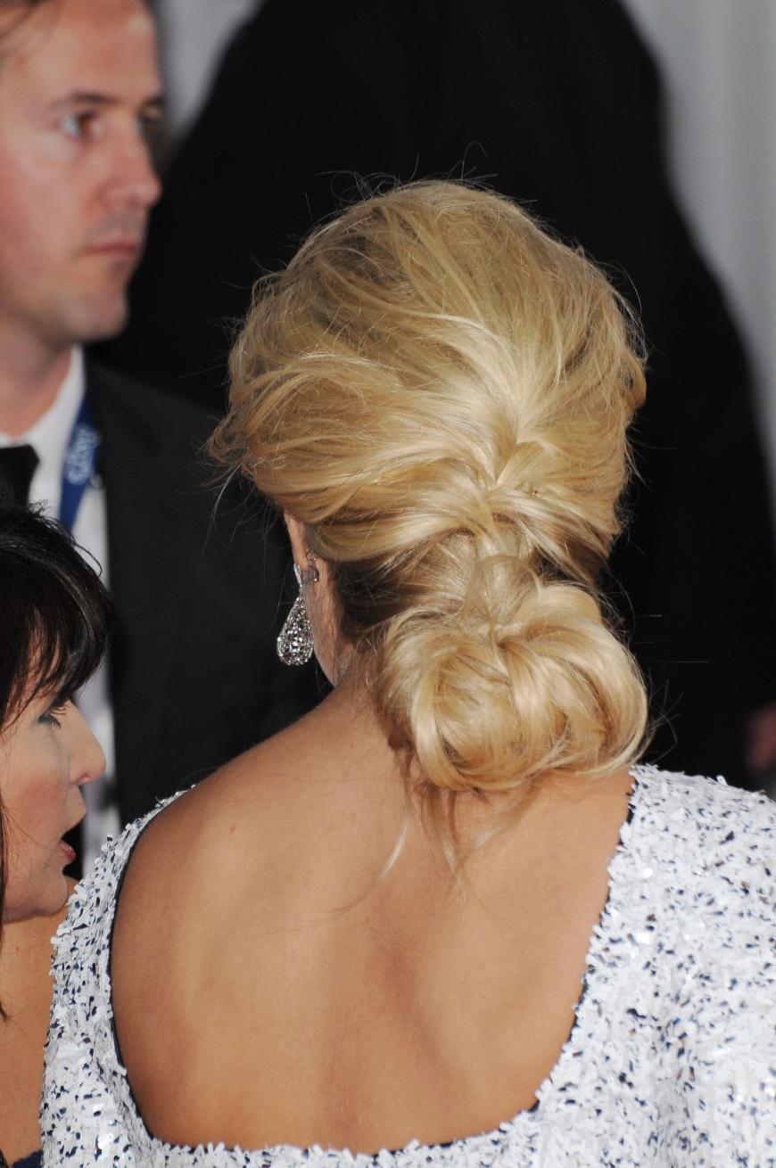 Die geflochtenen Partien werden unten in einem lockeren Chignon zusammengesteckt und passen perfekt zum tiefen Rückenausschnitt ihres Kleides.