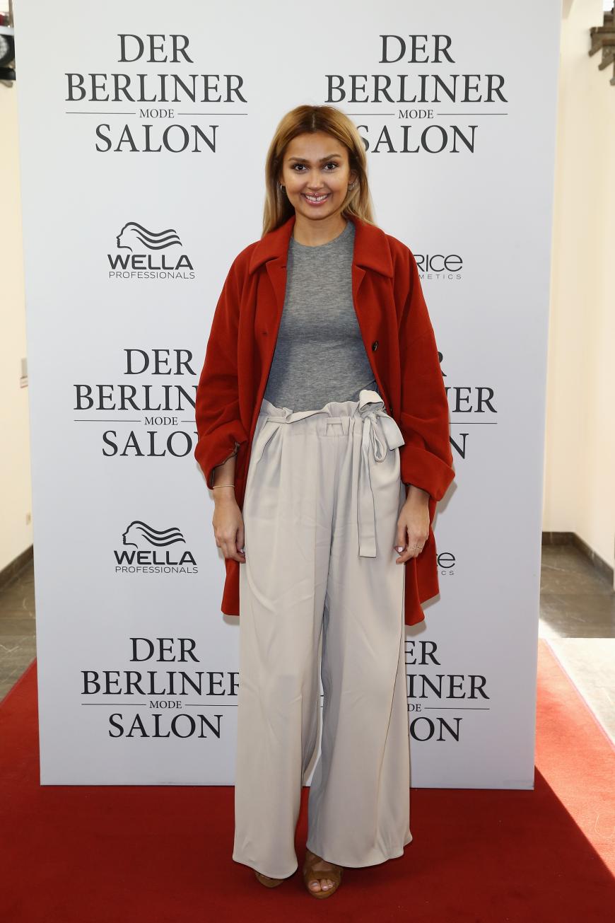 MTV-Moderatorin Wana Limar in einem super Look aus weißer Palazzohose, grauem Jerseyshirt und rotem Mantel.