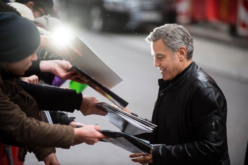 Bereitwillig gibt der Mann von Amal Clooney seinen deutschen Fans Autogramme.