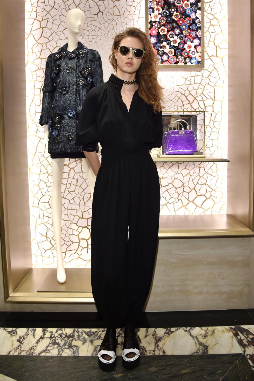 Nicht so elegant, dafür aber super cool: Lindsey Wixson in einem taillierten Jumpsuit mit Rundglas-Sonnenbrille, Plateausandalen und 90er-Jahre-Tattookette.