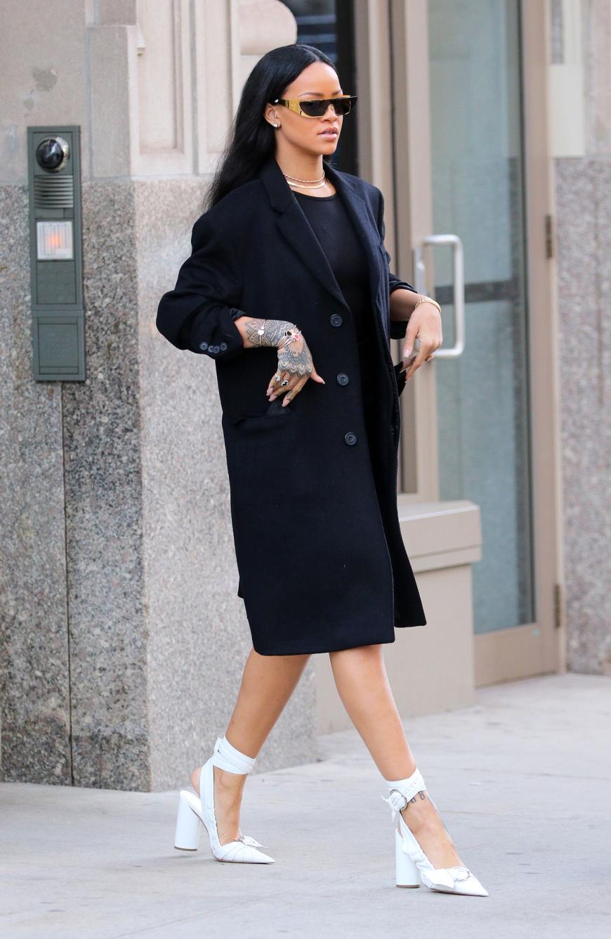 Rihanna trägt beim Verlassen ihres Apartments in SoHo, New York, einen schwarzen Mantel zu weißen Pumps und lässiger Sonnenbrille.