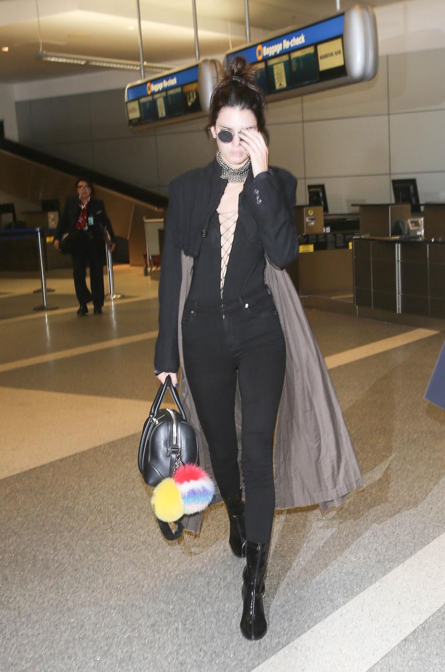 Auch am Flughafen überlässt Kendall Jenner beim Styling nichts dem Zufall und kombiniert ein geschnürtes Top zu Skinny Jeans und schwarz-grauem Duster.