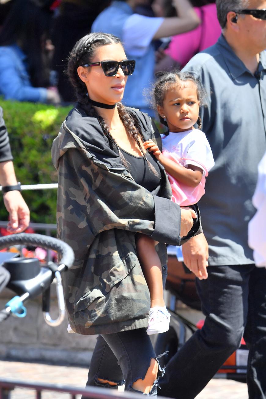 North West zieht eine süße Schnute während sie auf Mamas Arm durch Disneyland getragen wird.