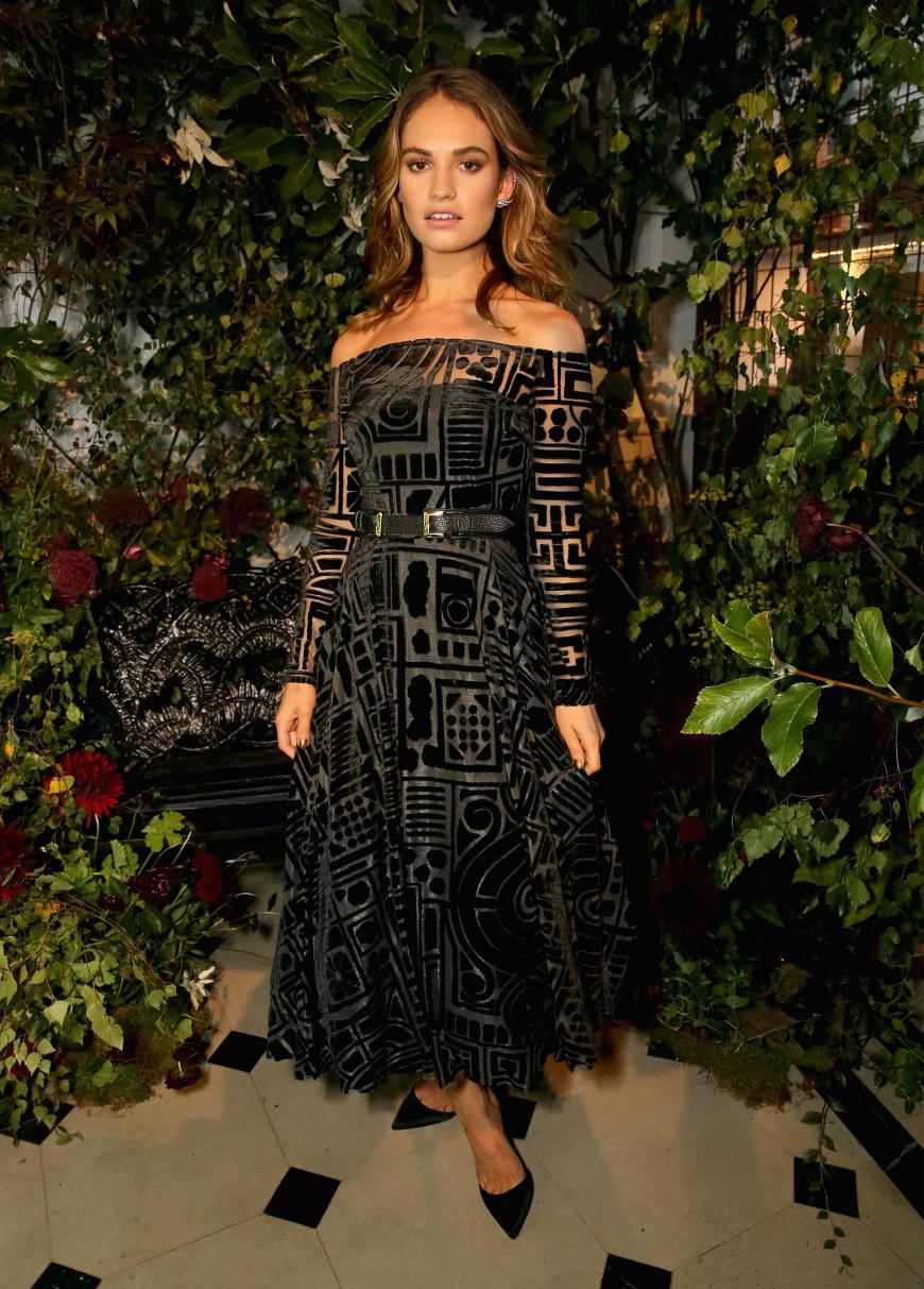 Das schulterfreie, leicht transparente Kleid mit Taillengürtel von Lily James gefällt uns auch!