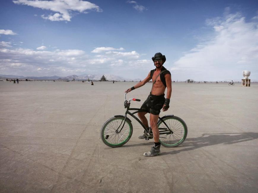 Thomas Hayo ist mit Fahrrad und oben ohne auf dem Burning Man unterwegs.