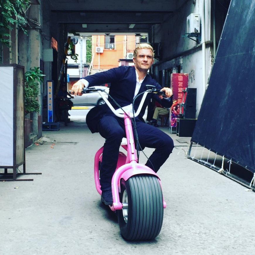 Orlando Bloom rollt mit blonden Haaren zum Set.