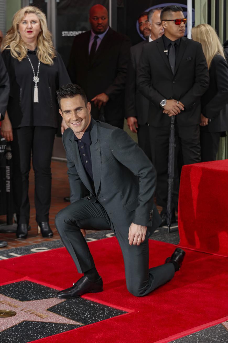 Adam Levine kniet über seinem