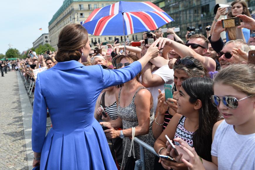 Kate strahlt mit ihrem königsblauen Outfit um die Wette - und die Zuschauer wollen sie mit einem Schirmchen im Great-Britain-Look zu sich locken.