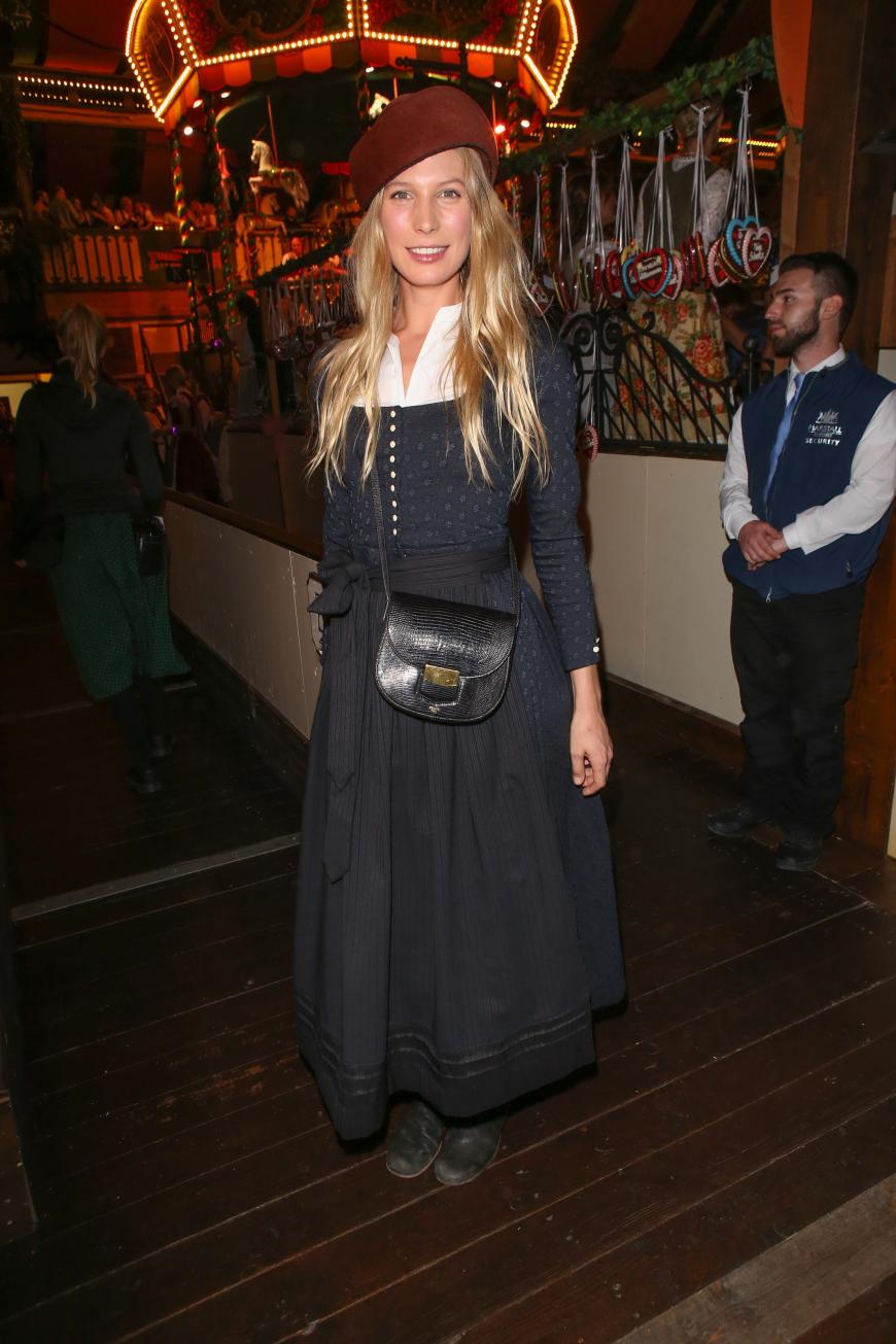 Wer kennt sie noch? Sarah Brandner, ehemals Bastian Schweinsteigers bessere Hälfte, kam mit einem eher ungewöhnlichen, aber coolen Outfit zum Oktoberfest. Das schwarzblaue Dirndl kombinierte die Blondine mit schwarzen Boots und einer Retro-Handtasche.