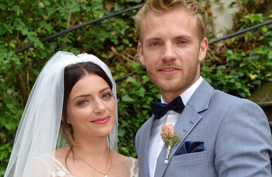 Folge 6568, 08. August 2018: Endlich treten Emily, gespielt von Anne Menden, und Handwerker Paul, gespielt von Niklas Osterloh, vor den Traualtar. In den vergangenen Monaten muss das Paar so einiges durchstehen. So taucht zum Beispiel die verschollene Schwester von Paul wieder im GZSZ-Kiez auf. Doch es stellt sich heraus, dass die junge Frau sich nur in das Leben des Handwerkers zeckt, um ein Buch zu schreiben. Das haben Emily und Paul aber alles überwunden und schwören sich die ewige Liebe.