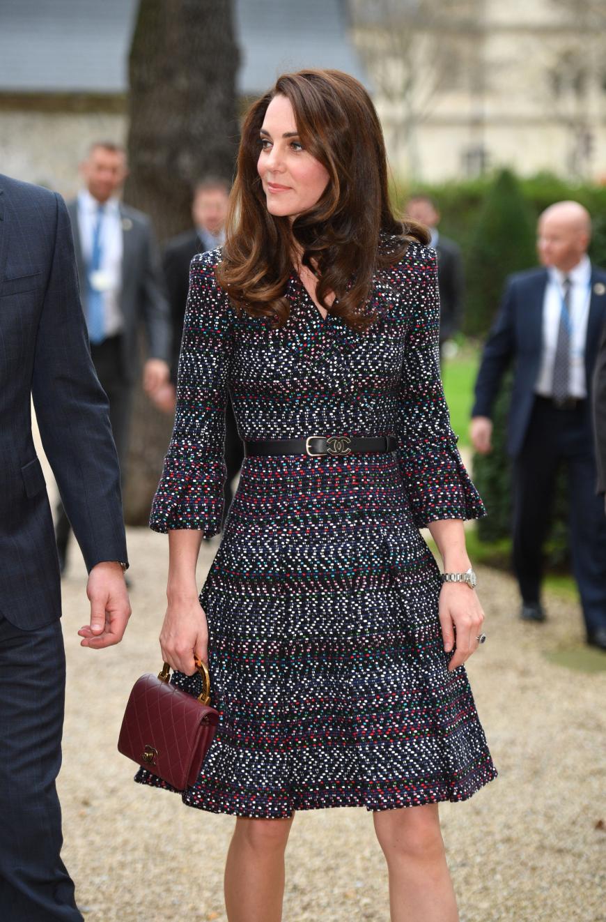 Während ihres Aufenthalts in Paris entzückte Kate in einem Mantel aus Tweed von Chanel. Hingucker sind die Accessoires: Zu ihrem Mantel kombinierte sie einen Taillengürtel und eine bordeauxrote Handtasche des Pariser Modelabels.