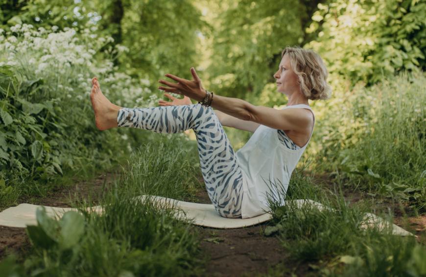 Boot = Ardha Navasana: Für diese Übung setzt du dich auf deine Yogamatte, greifst deine Oberschenkel und aktivierst deine Bauchmuskulatur. Löse deine Füße vom Boden und lass deine Waden parallel zur Matte schweben. Deine Wirbelsäule wird aufgerichtet, dein Herzraum weit, deine Atmung fließt weich. 5-10 Atemrunden.