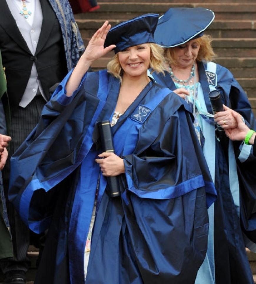 In blauer Kutte strahlt Kim Cattrall über das ganze Gesicht