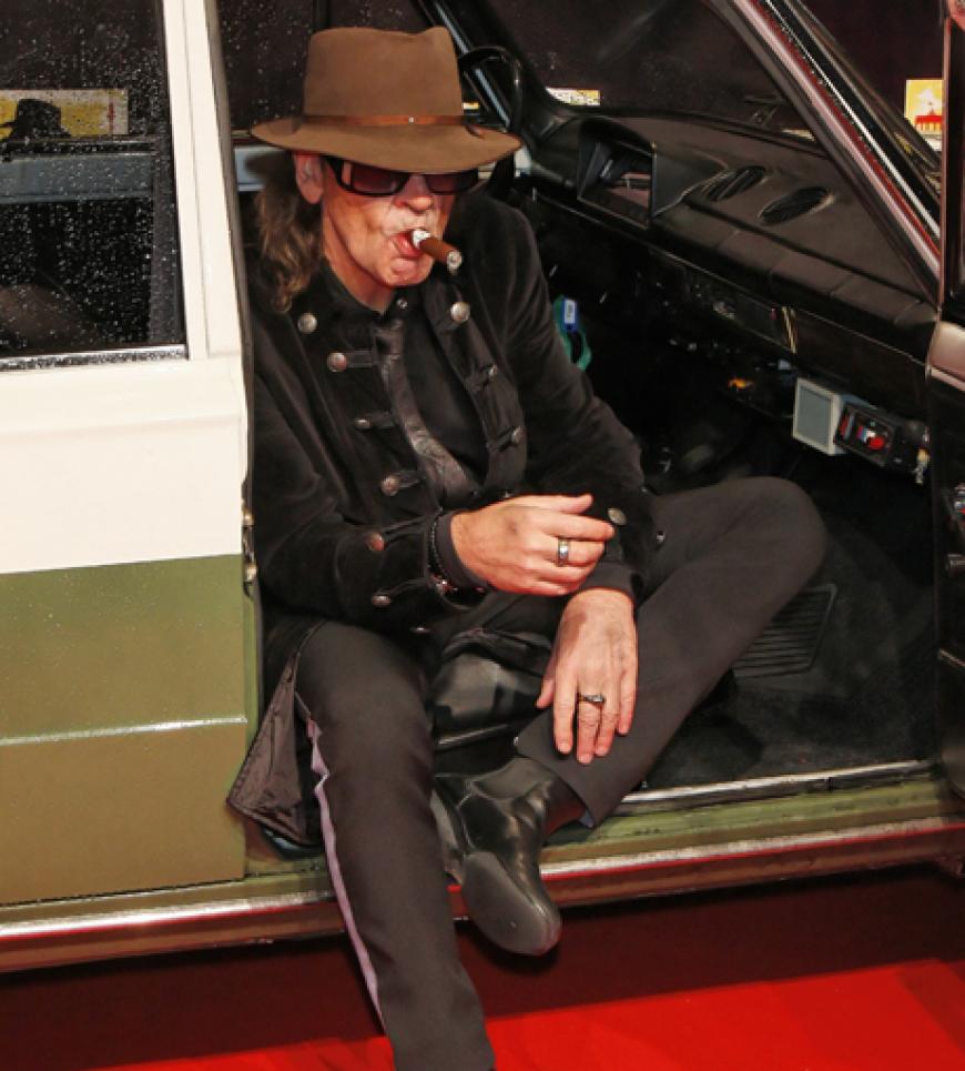 Der 64-jährige Udo Lindenberg posiert auf dem roten Teppich in einem Oldtimer.