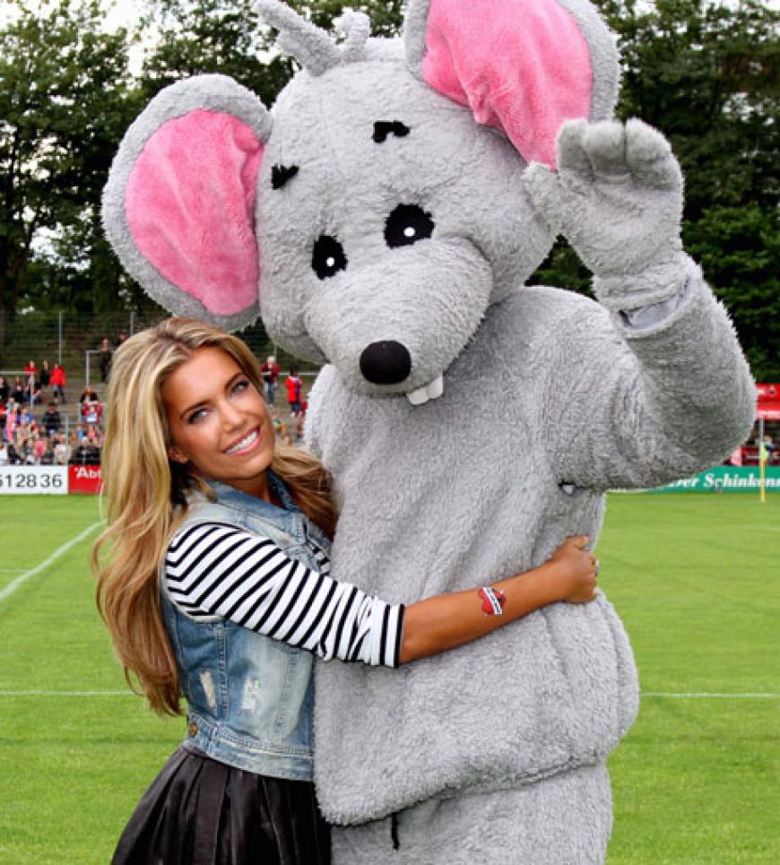 Die Moderatorin strahlt mit dem Maskottchen für die Kameras
