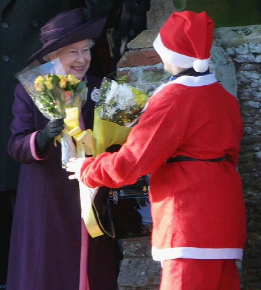 Queen Elisabeth II bekommt von einem verkleideten Santa Claus Blumen überreicht