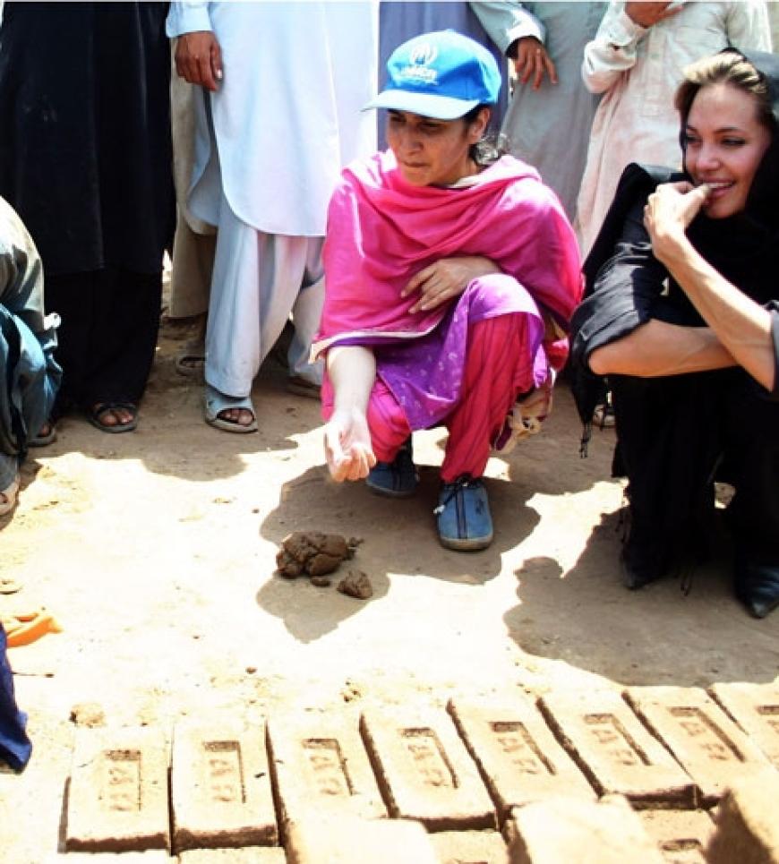Angelina schaut einem Flüchtlings-Mädchen in Islamabad zu, wie sie Ziegelsteine anfertigt