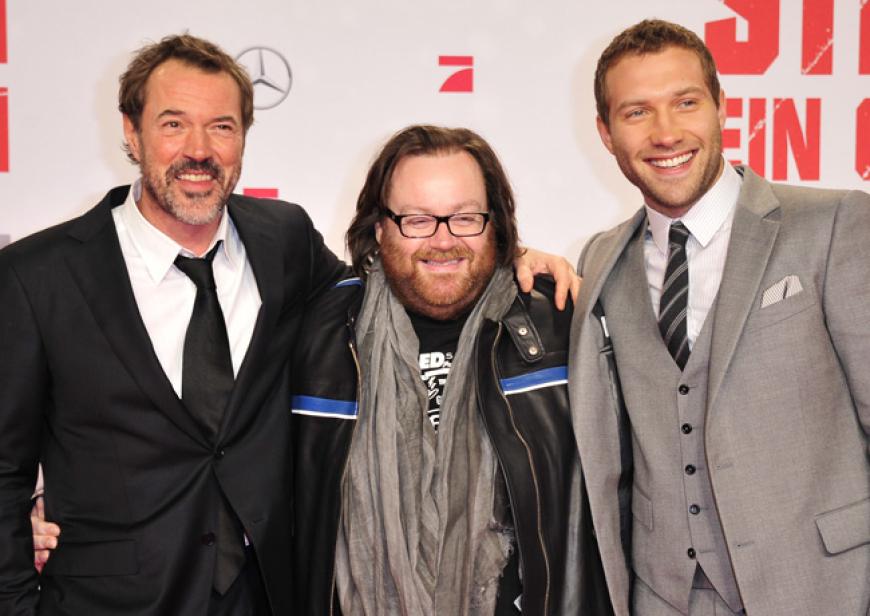 Der deutsche Schauspieler Sebastian Koch spielt den Gegenspieler von Bruce Willis. In Berlin posierte er mit Regisseur John Moore und Jai Courtney