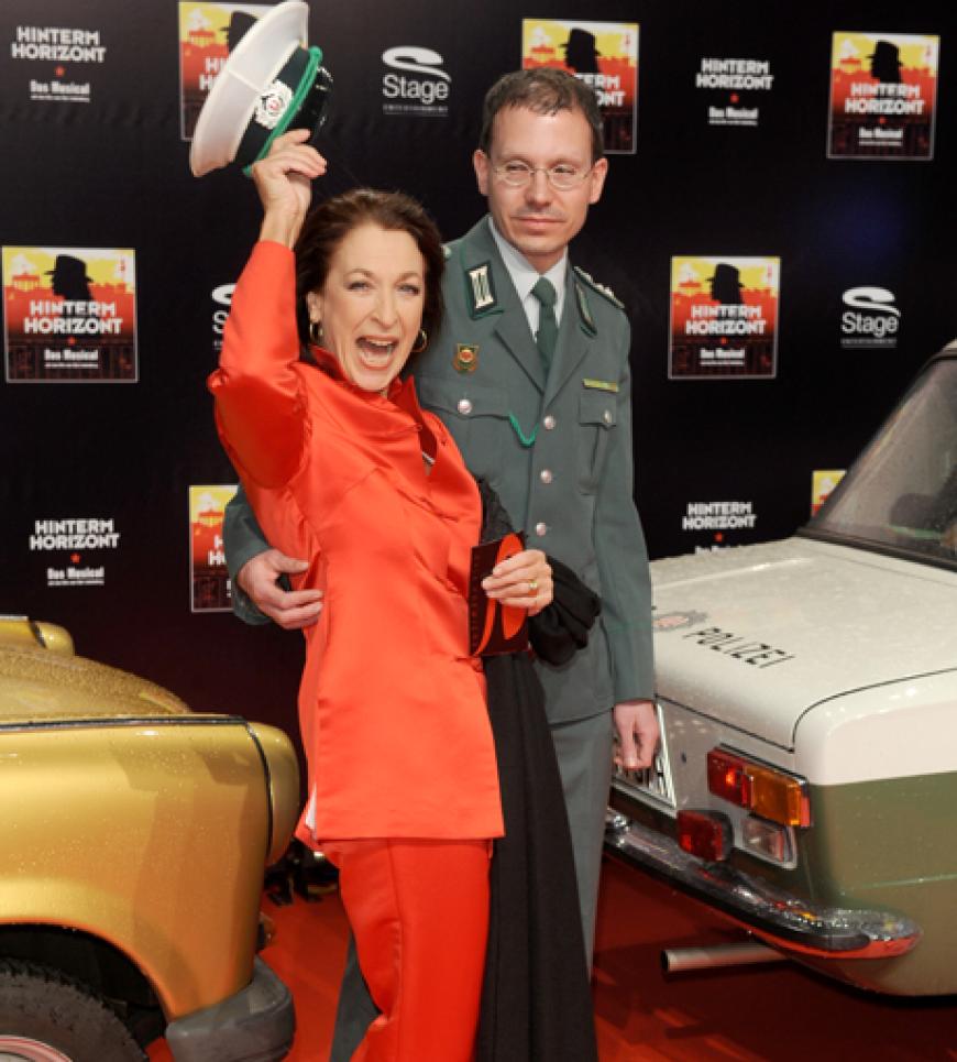 Ein Statist in der Uniform der DDR-Volkspolizei begleitet Schauspielerin Daniela Ziegler in den Kinosaal