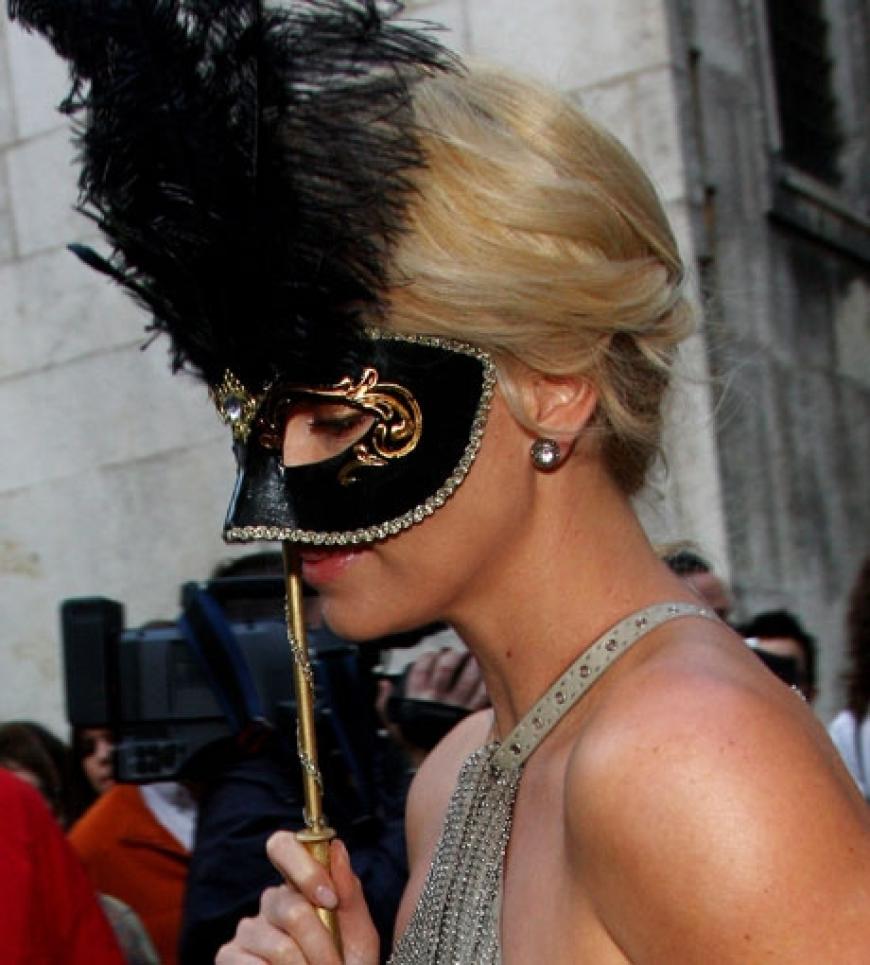 Schauspielerin Charlize Theron hält sich eine Maske vors Gesicht - als Anspielung auf die venezianische Tradition der Maskenbälle