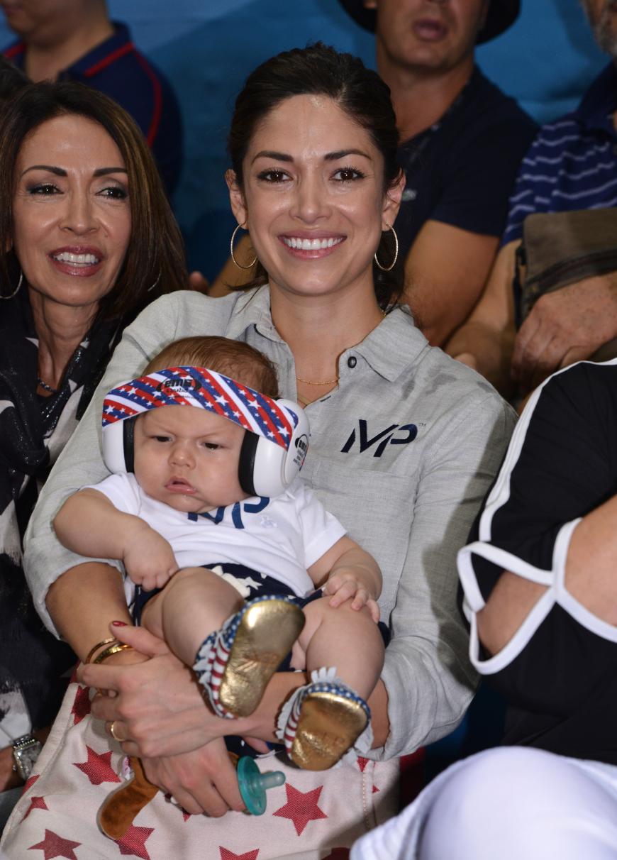 Olympia, Baby! Nicole Johnson schaut mit Söhnchen Boomer den olympischen Schwimmwettbewerb von Michael Phelps an. Der Kleine trägt schon mal goldene Schühchen und USA-Kopfhörer.