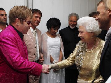 Elton John schüttelt der lächelnden Queen Elizabeth die Hand