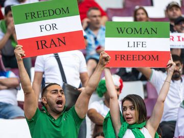 Iraner und Iranerin halten bei WM 2022 in Katar Protest-Schilder hoch